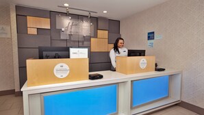 Un comptoir d’accueil d’hôtel au design moderne, doté d’un écran numérique et d’une enseigne indiquant le nom de l’hôtel.