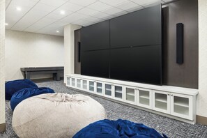 A modern living room with a large flat-screen TV, a white entertainment unit, and two bean bags.