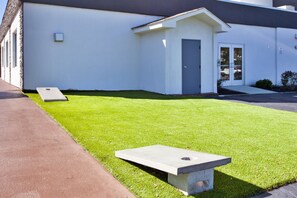 A modern building with a flat roof, a small entrance, and a well-maintained lawn with two concrete benches.