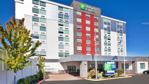 Un hôtel Holiday Inn Express doté d’une façade moderne, de grandes fenêtres et d’un mur d’accent rouge bien visible.