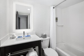 Bathroom features a sink, mirror, toilet, and shower, with a towel rack and toiletries nearby.