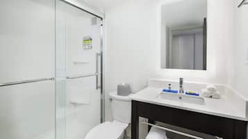Un baño moderno con cabina de ducha de vidrio, inodoro blanco y tocador con espejo.