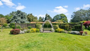 Ein Garten mit einer hölzernen Bank und einem Metallbogen.