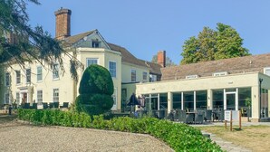 Ein Innenhof mit Kiespflaster, einem ordentlich geschnittenen Heckenstreifen und einem Gebäude mit großen Fensterflächen.