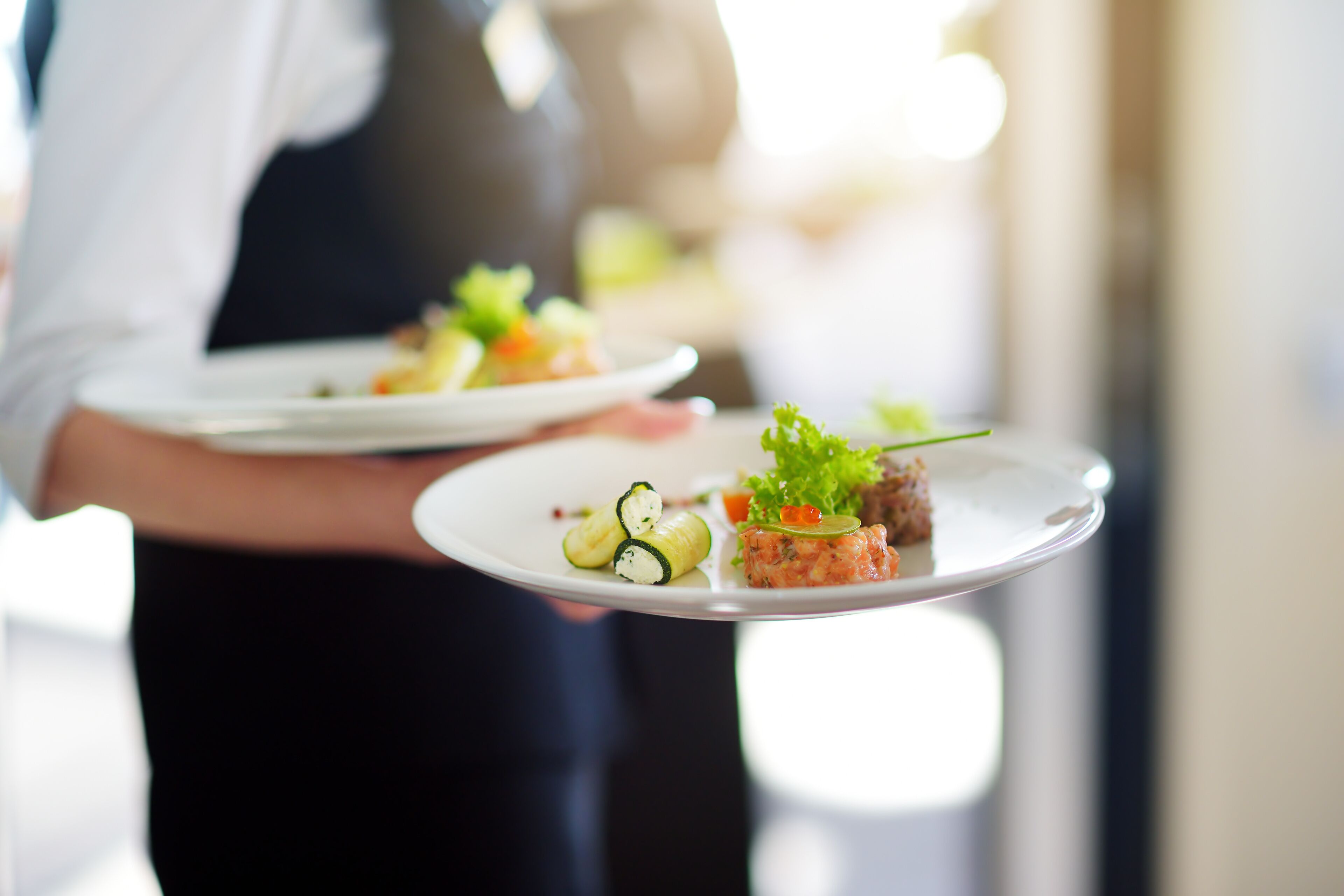 A person holding a plate with various food items.