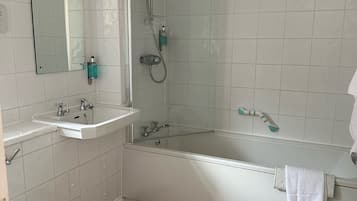 A bathroom with a toilet, two sinks, a bathtub, and a shower.