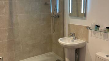 A modern bathroom with a glass shower enclosure, a white sink, and a toilet.