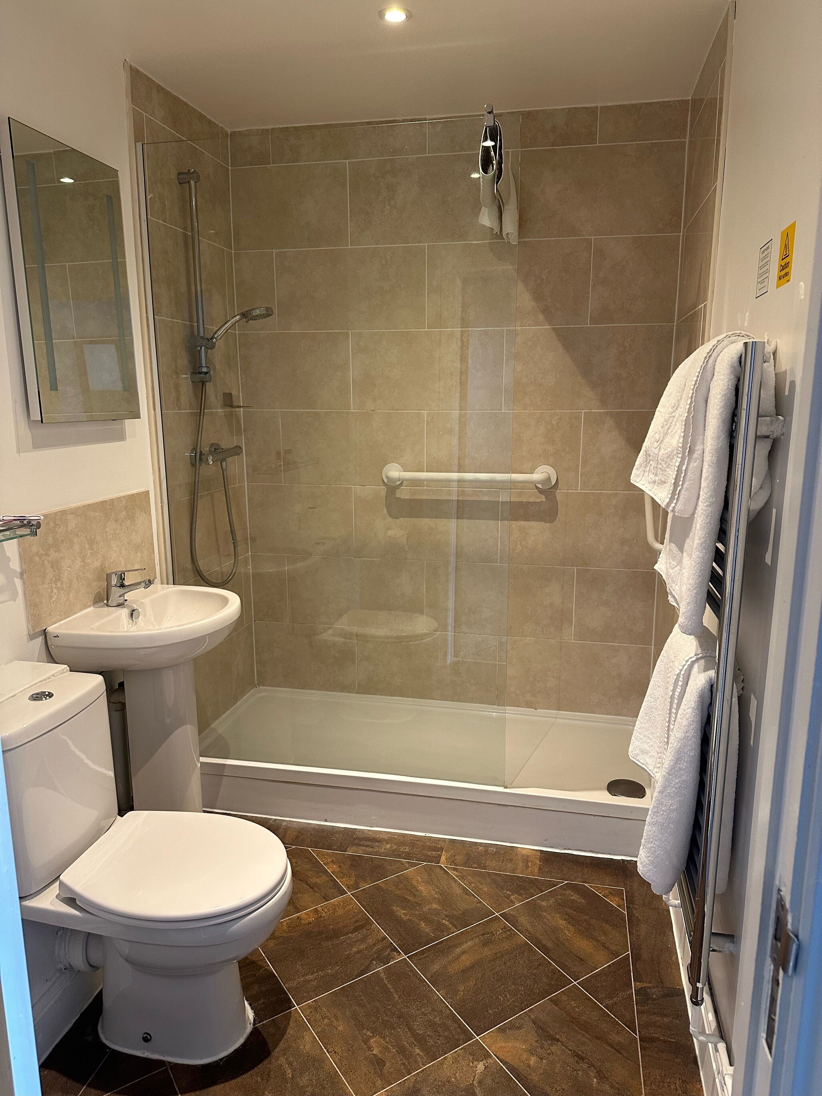 Une salle de bain avec une douche à parois de verre, des toilettes et un lavabo.