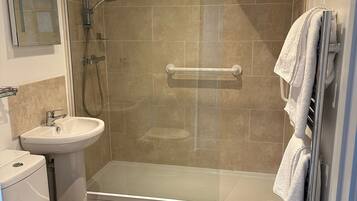 Une salle de bain avec une douche à parois de verre, des toilettes et un lavabo.