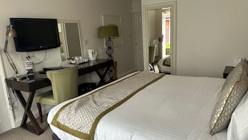 Quarto de hotel com uma cama grande, uma escrivaninha com computador, uma televisão e uma cadeira.