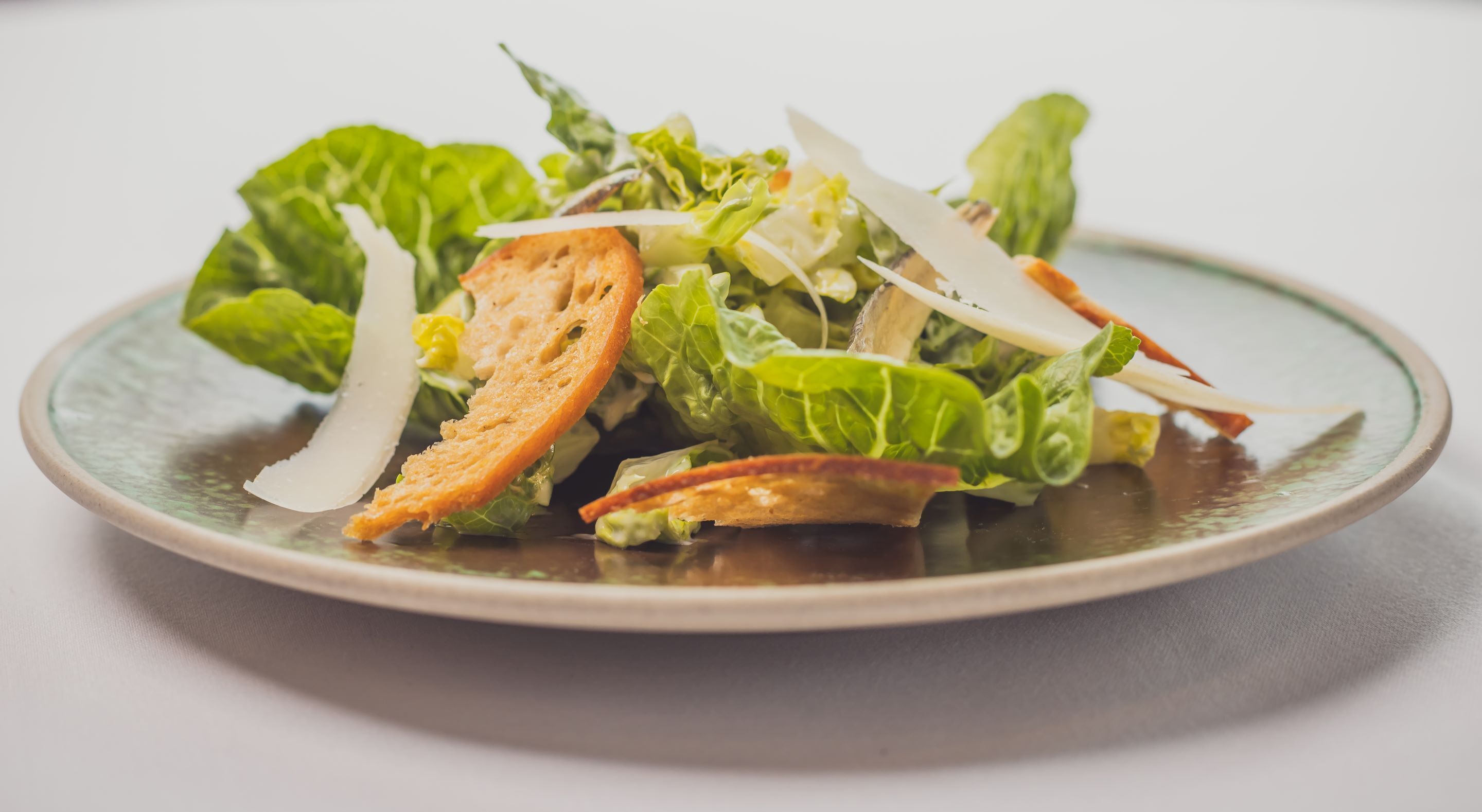 A plate of salad with greens and croutons.