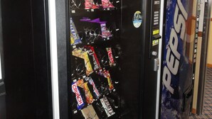 A vending machine stocked with snacks and beverages, including a Pepsi dispenser.