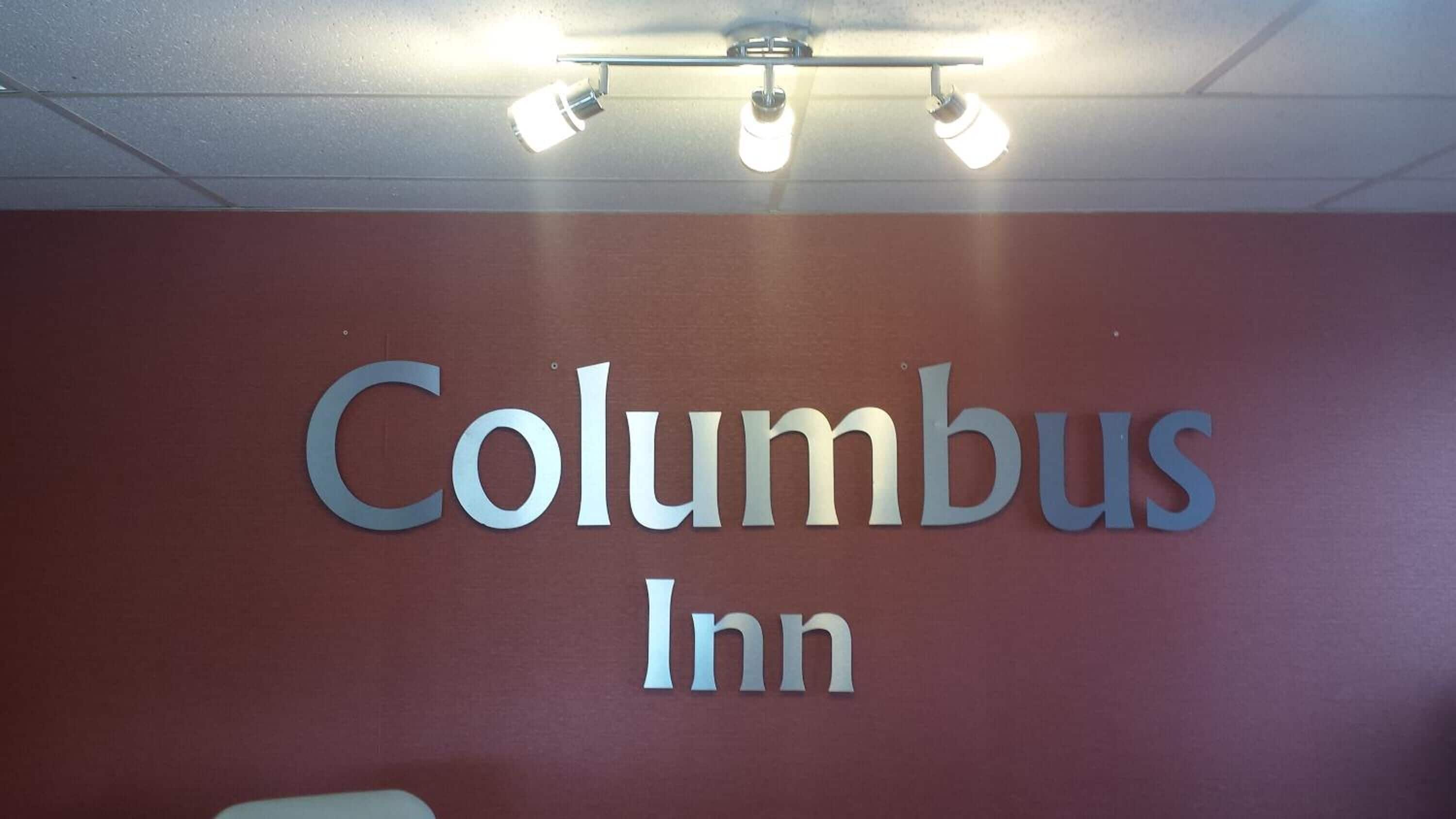 A sign for Columbus Inn with a ceiling light fixture above it.