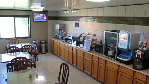 A restaurant with a counter, seating area, and a television screen.