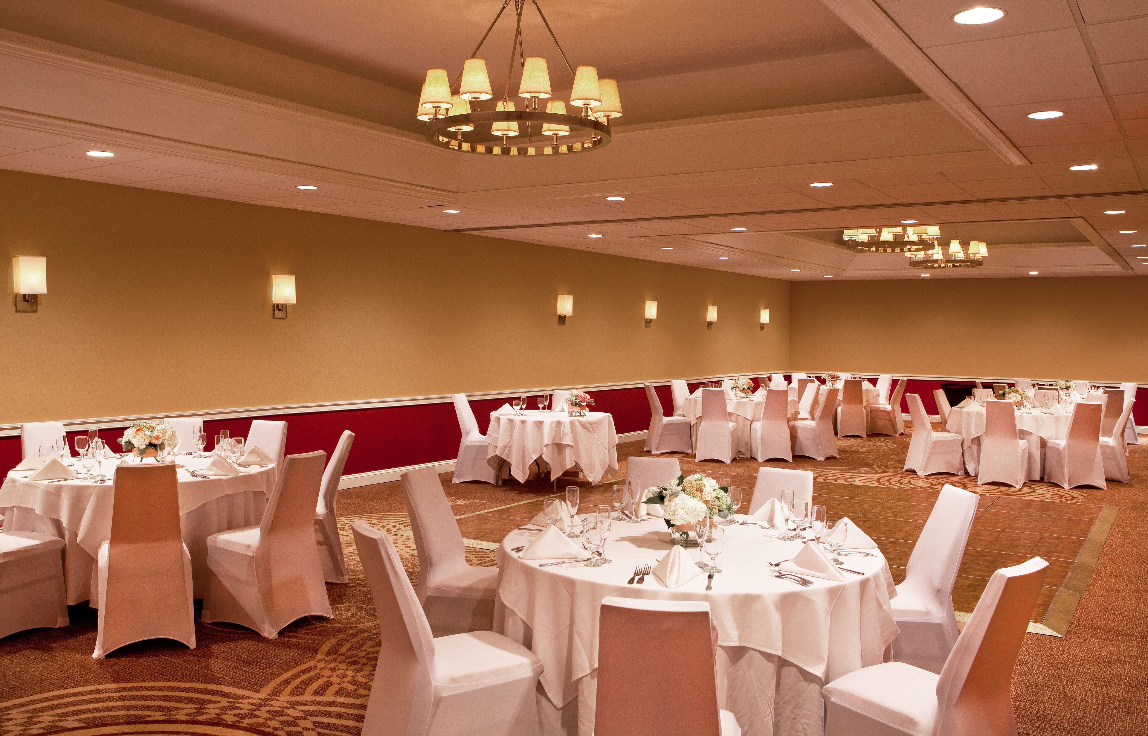 Un salón de banquetes con mesas redondas, manteles blancos y sillas.