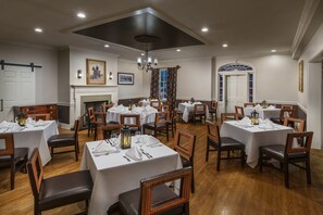 A dining area with round tables, wooden chairs, and white tablecloths. - Sheraton Great Valley Hotel (Malvern)
