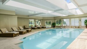 An indoor swimming pool with lounge chairs and large windows. - Sheraton Great Valley Hotel (Malvern)