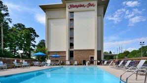 Um Hampton Inn com piscina, cadeiras de sol e guarda-sóis.