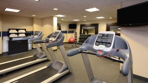 Uma academia com esteiras, bolas de exercícios e halteres.