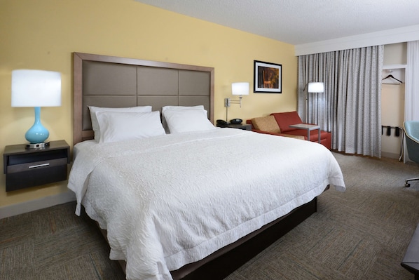 Une chambre d’hôtel avec un grand lit, un bureau, une chaise, une lampe et une armoire.