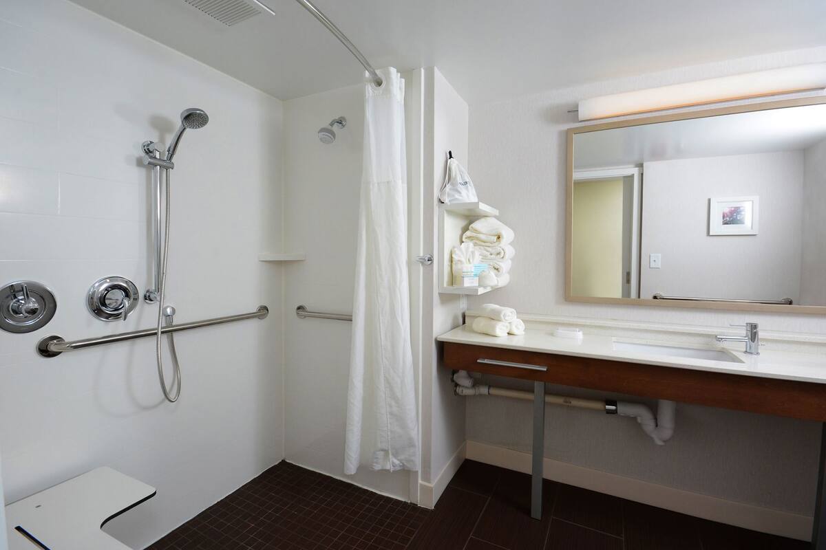 A bathroom with a shower, a sink with a mirror, and a towel rack.