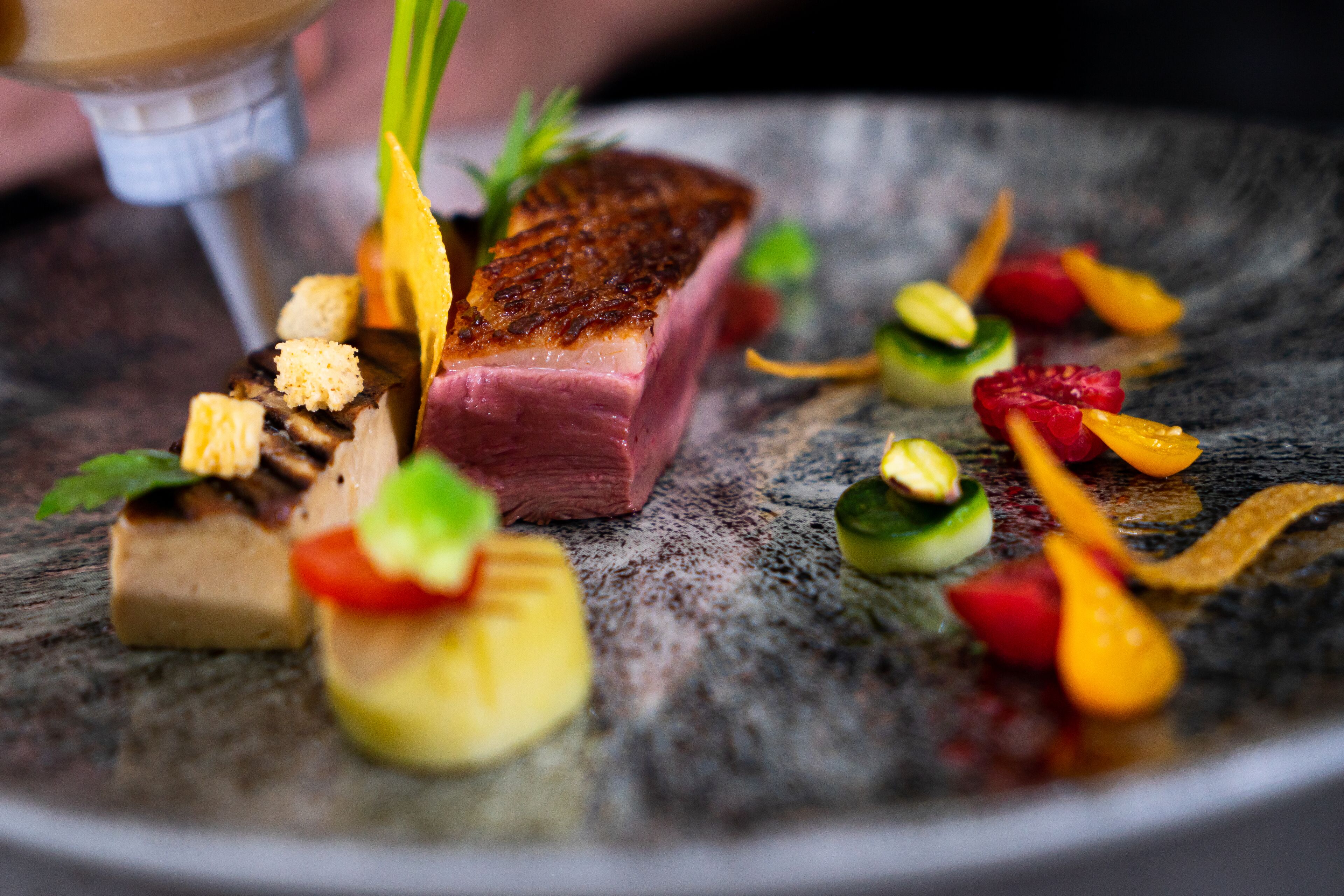 Un plato con carne a la parrilla, verduras y adornos.