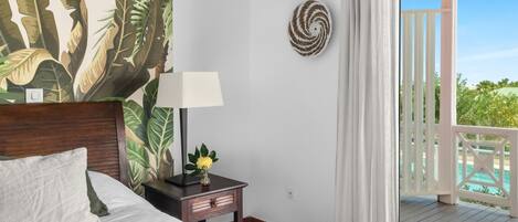 Un dormitorio con cama, mesita de noche, lámpara y vistas a un balcón.