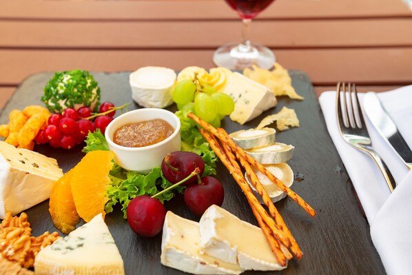 A charcuterie board with various cheeses, fruits, and crackers on a slate board. - Dorint Hotel Leipzig (Leipzig)