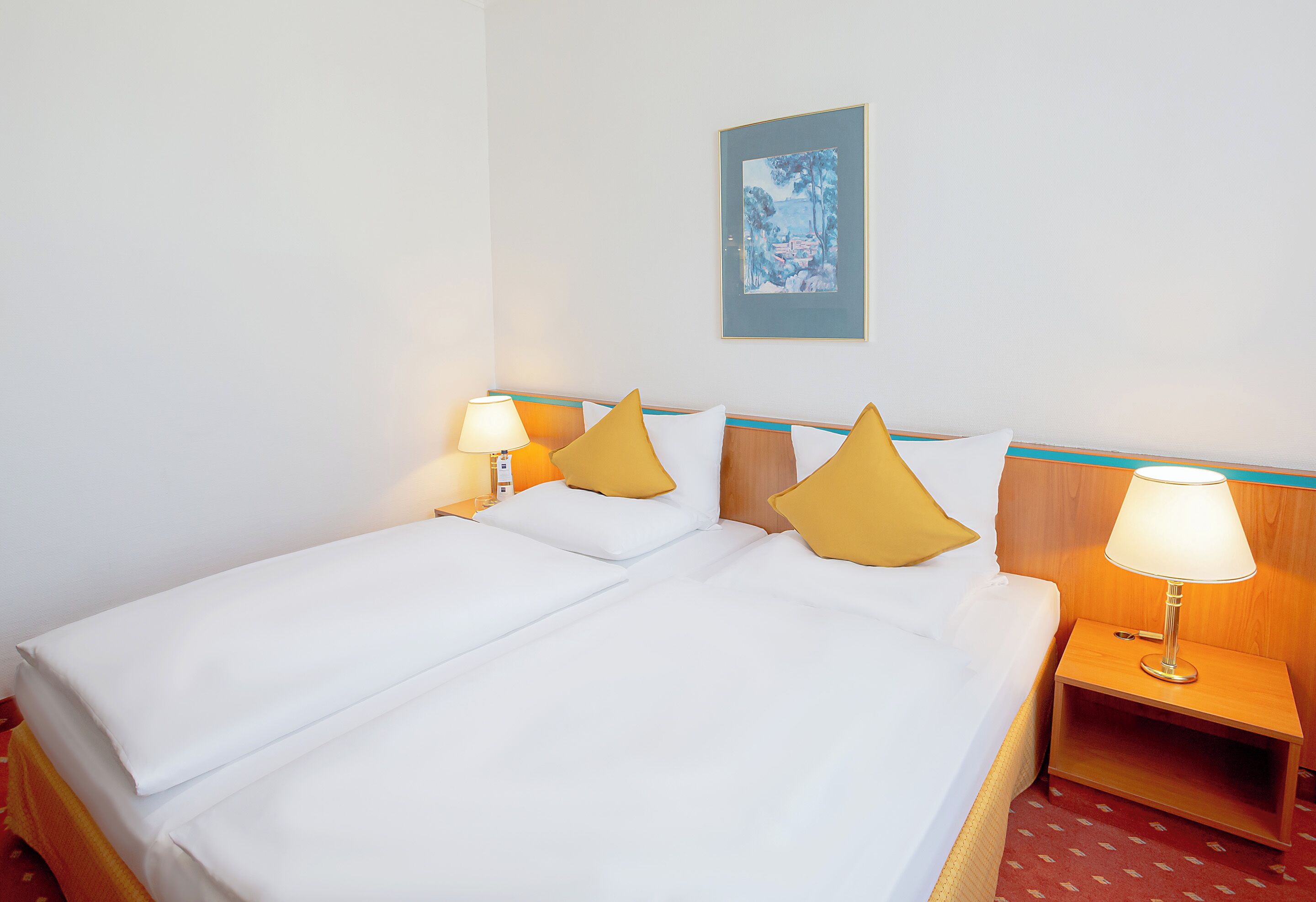 Una habitación de hotel con una cama, dos mesitas de noche, una lámpara y un cuadro en la pared.