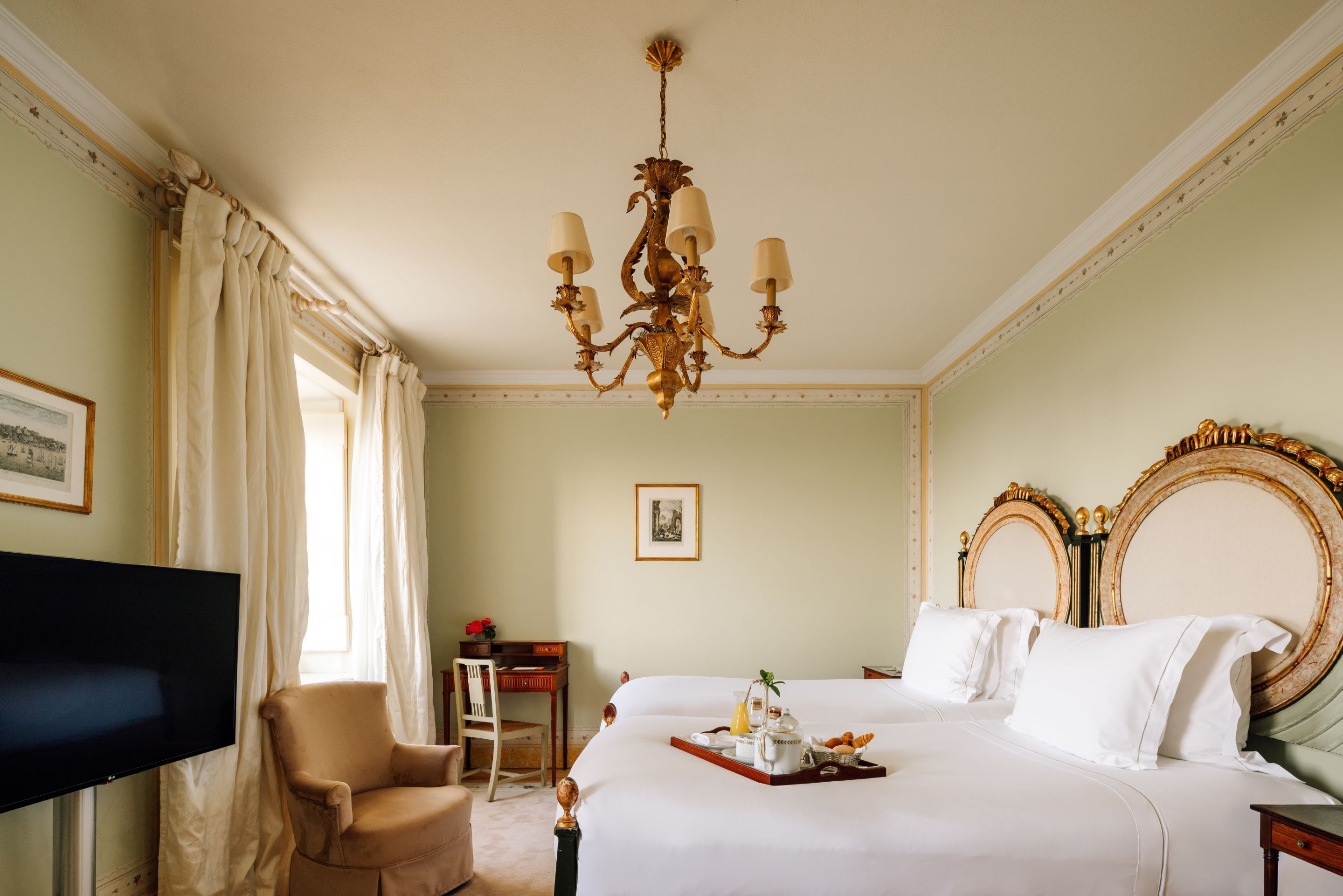 Una habitación de hotel con una cama grande, televisión, escritorio y candelabro.