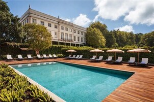 Una piscina al aire libre, sillones reclinables de piscina