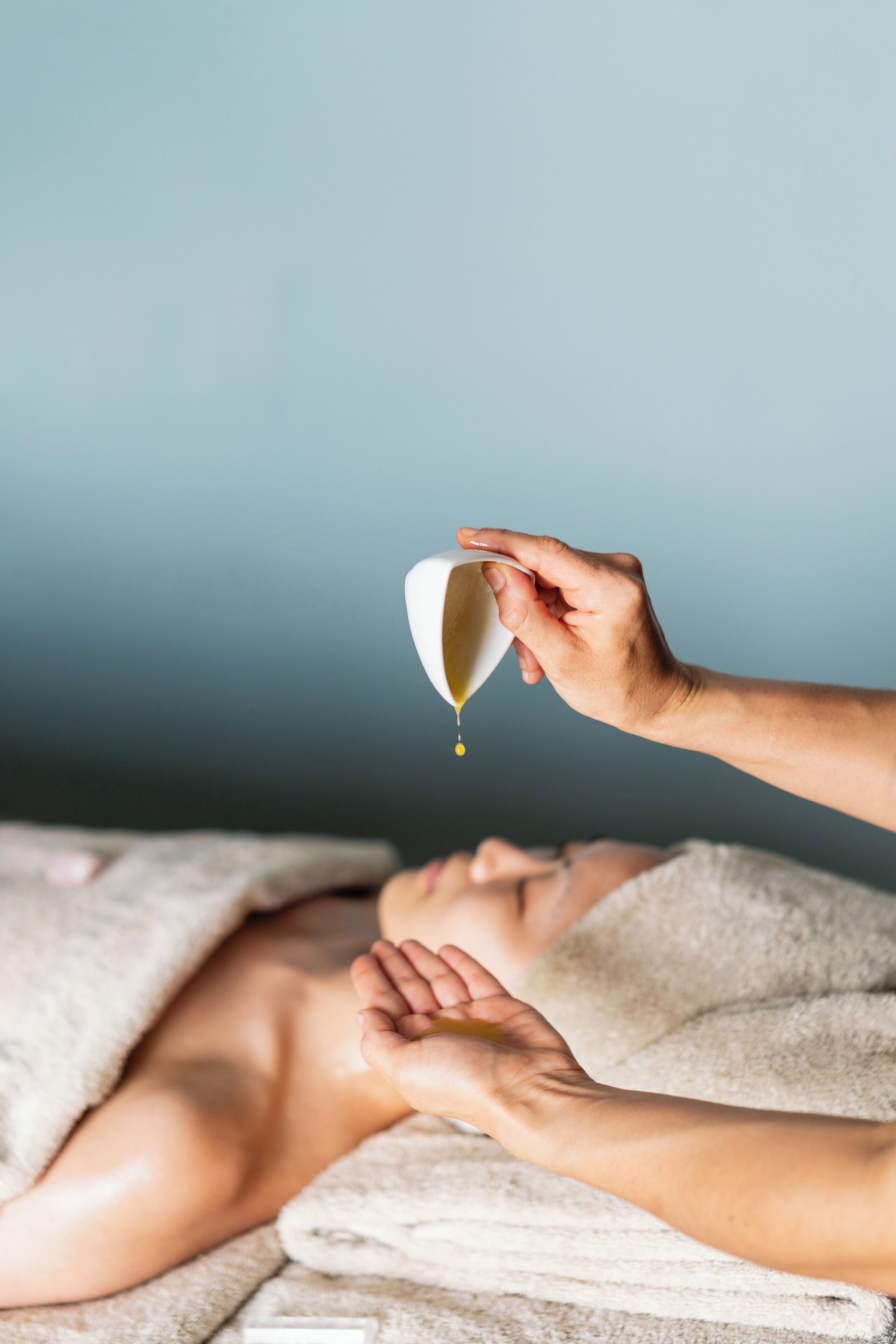 A person receiving a massage with a towel and a white cup.