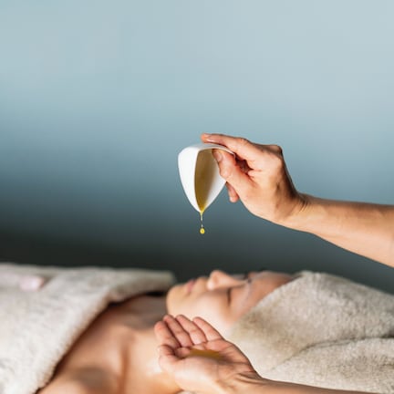 A person receiving a massage with a towel and a white cup.