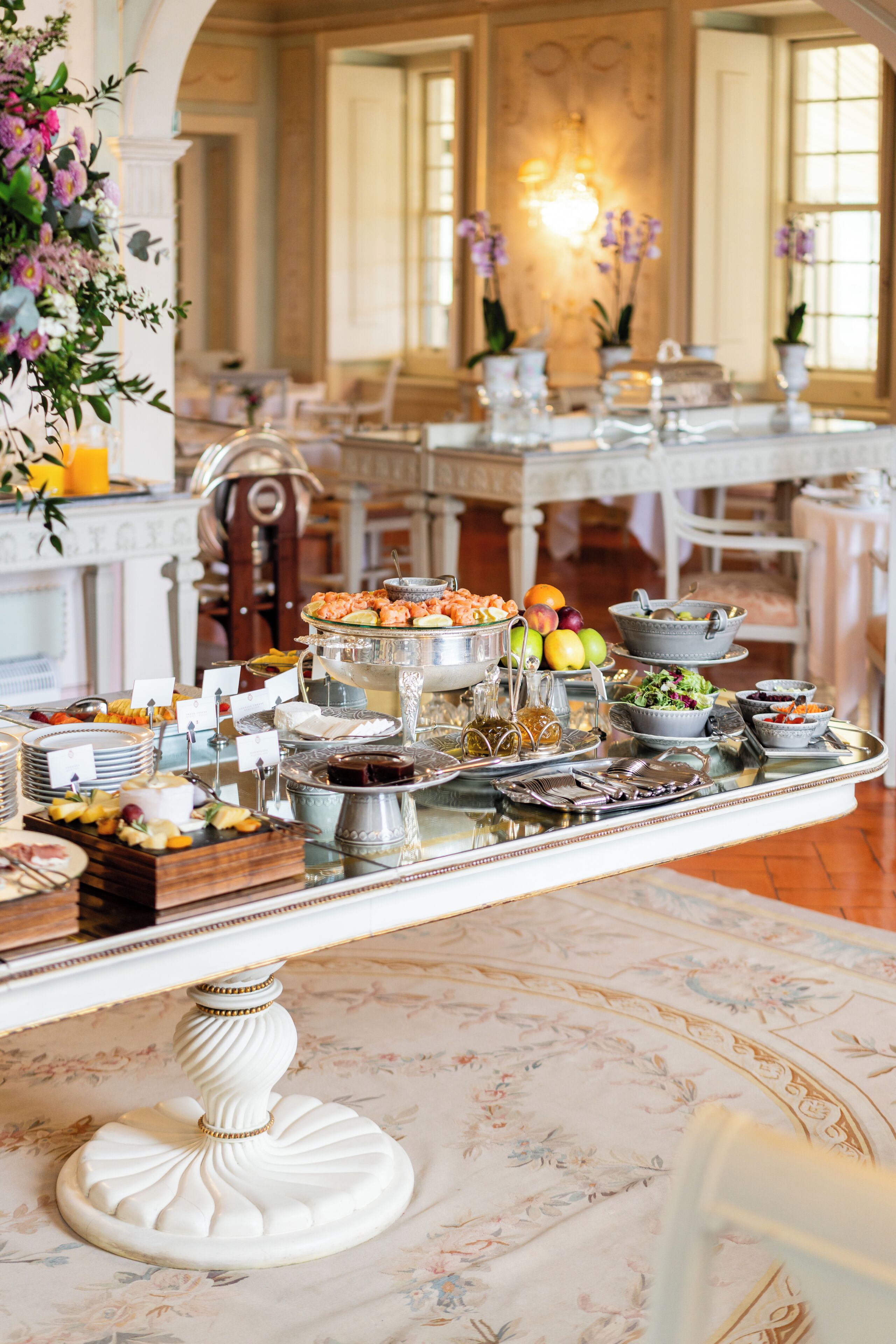 A buffet setup with various food items and a floral arrangement.