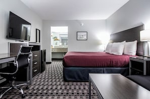 A hotel room with a bed, desk, chair, television, and a bathroom visible through an open door.