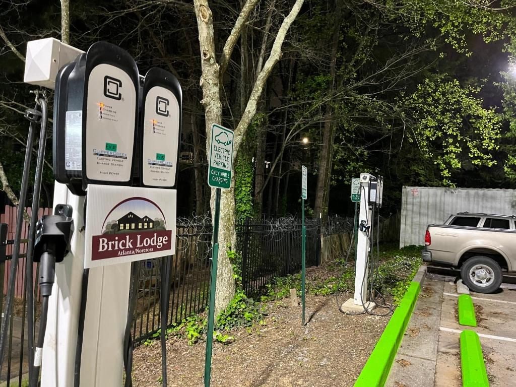 Estações de carregamento para veículos elétricos, placa de estacionamento e placa de pedra indicando uma hospedaria.