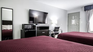 Een hotelkamer met twee bedden, een televisie, een bureau met stoel, en een deur.
