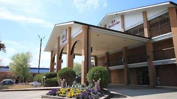 Un hotel con entrada cubierta, un letrero que dice 'Brick Lodge' y un estacionamiento.