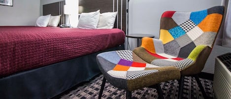 A hotel room with a bed, a chair, and a bedside table.