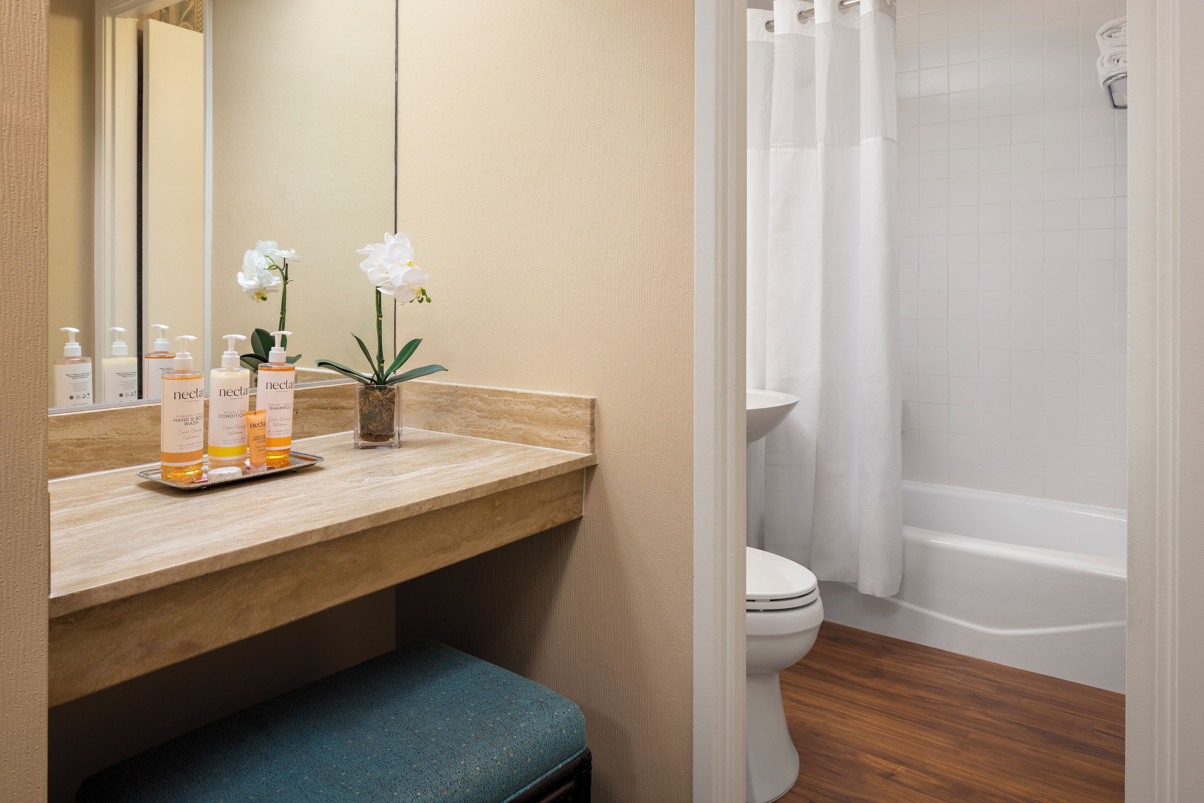 A bathroom with a wooden vanity, a toilet, a bathtub, and a shower curtain.