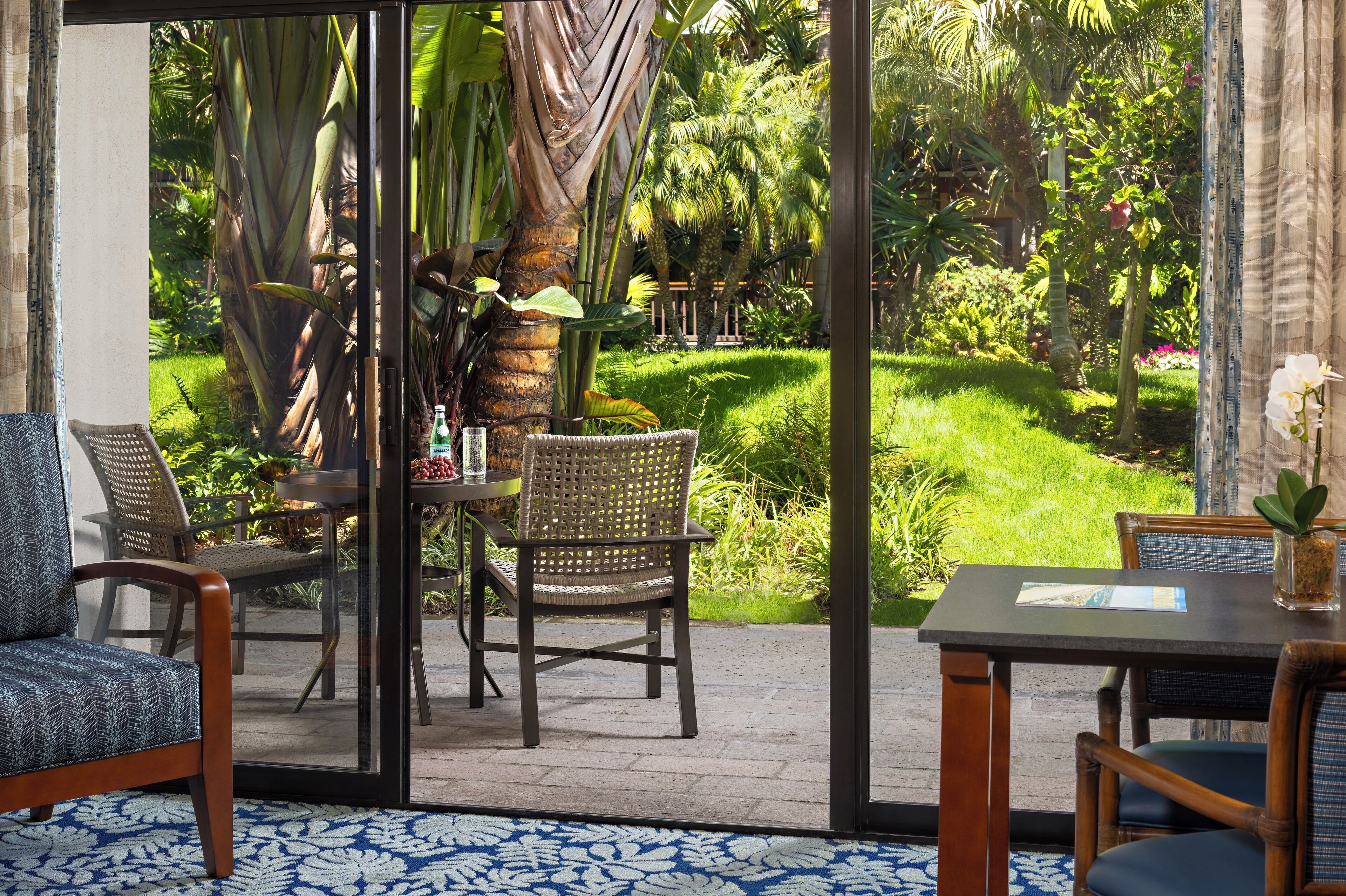 Uma estufa com porta de vidro, móveis de vime e vista para um jardim exuberante.