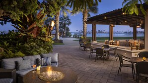 An outdoor patio with seating, a fire pit, and a view of the ocean. - Catamaran Resort and Spa (San Diego)