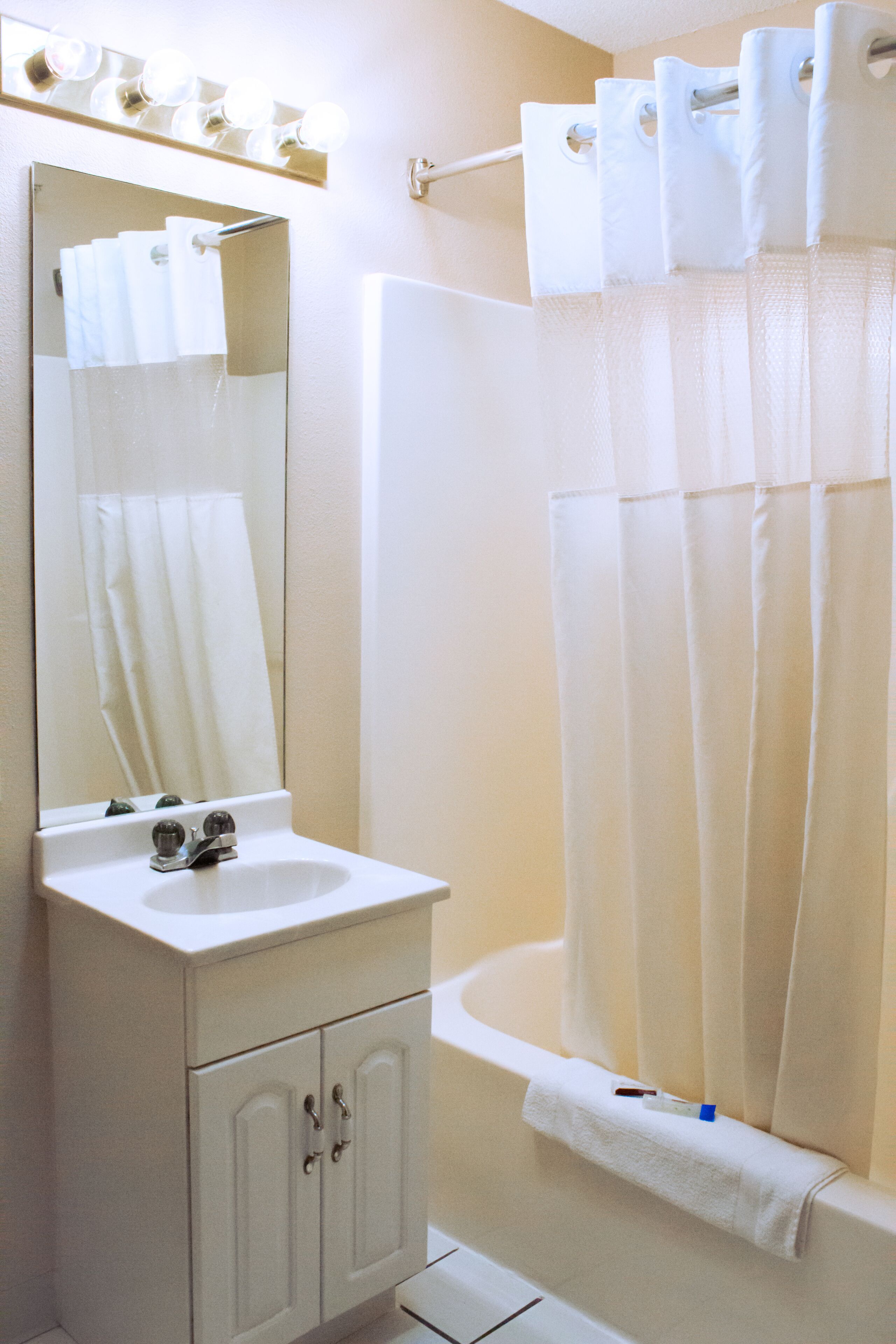 A bathroom with a sink, mirror, and shower curtain.