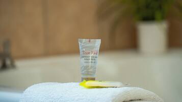 A bathroom with a white towel, a shampoo bottle, and a plant in the background.