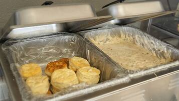 A buffet setup with two covered serving trays, one containing biscuits and the other a creamy spread.