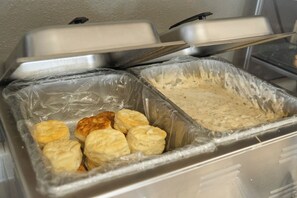 A buffet setup with two covered serving trays, one containing biscuits and the other a creamy spread.