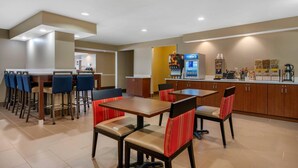 A hotel lobby with a dining area featuring tables and chairs, a coffee machine, and a vending machine. - Comfort Inn Ocala Silver Springs (Ocala)