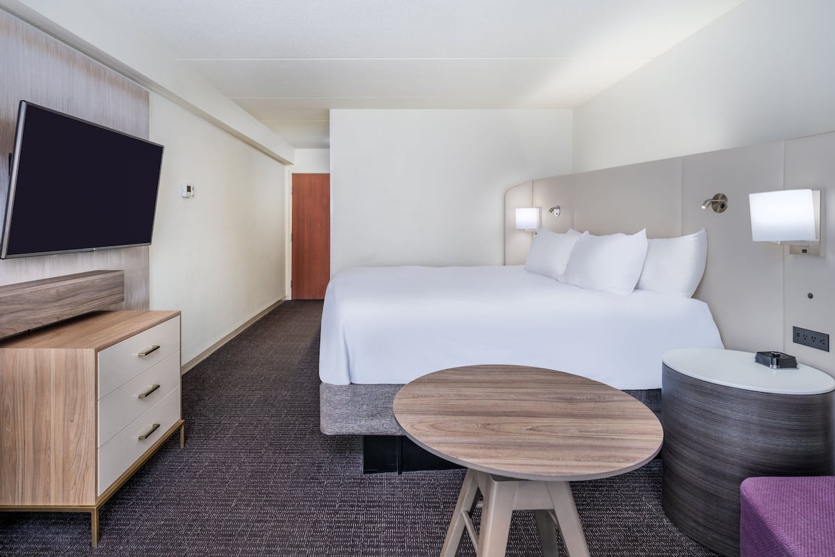 Une chambre d’hôtel avec un lit, une télévision, un bureau et une petite table.