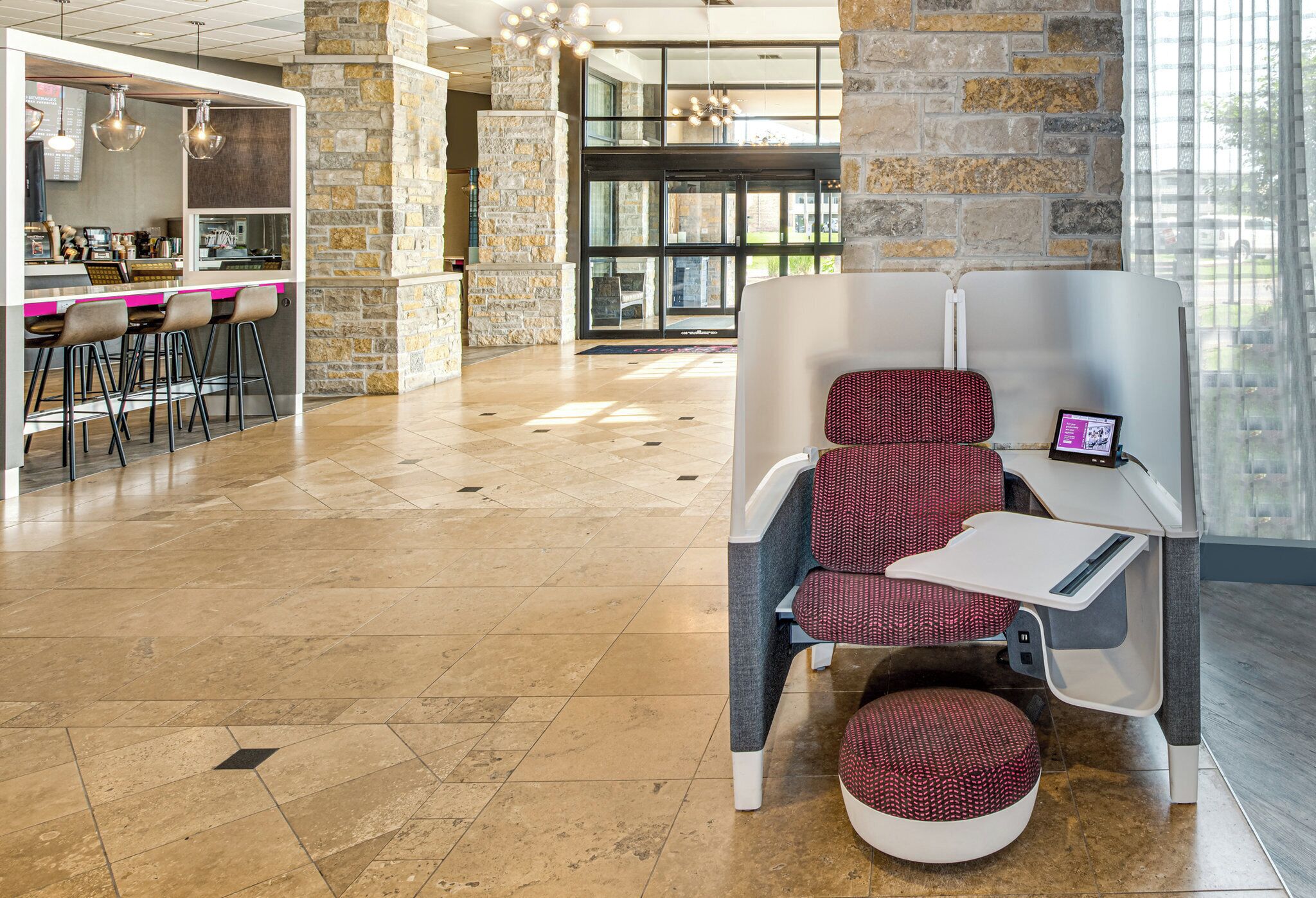 A modern lounge area with a stone accent wall, a bar with stools, and a seating area with a tablet.