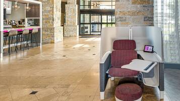 A modern lounge area with a stone accent wall, a bar with stools, and a seating area with a tablet.